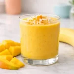 Mango turmeric smoothie in a glass with creamy texture and fresh mango slices