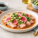 Hamachi crudo plated with thin yellowtail slices, radish, cucumber, serrano, and citrus-soy dressing