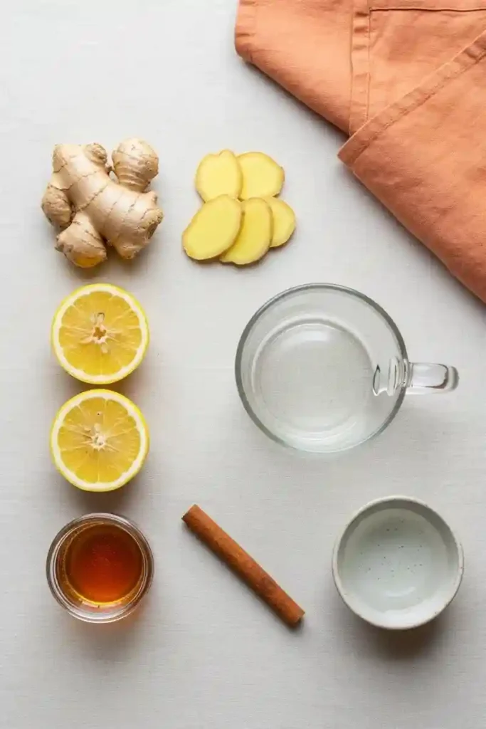 Fresh ginger, lemon slices, cinnamon, and honey styled on soft cream background